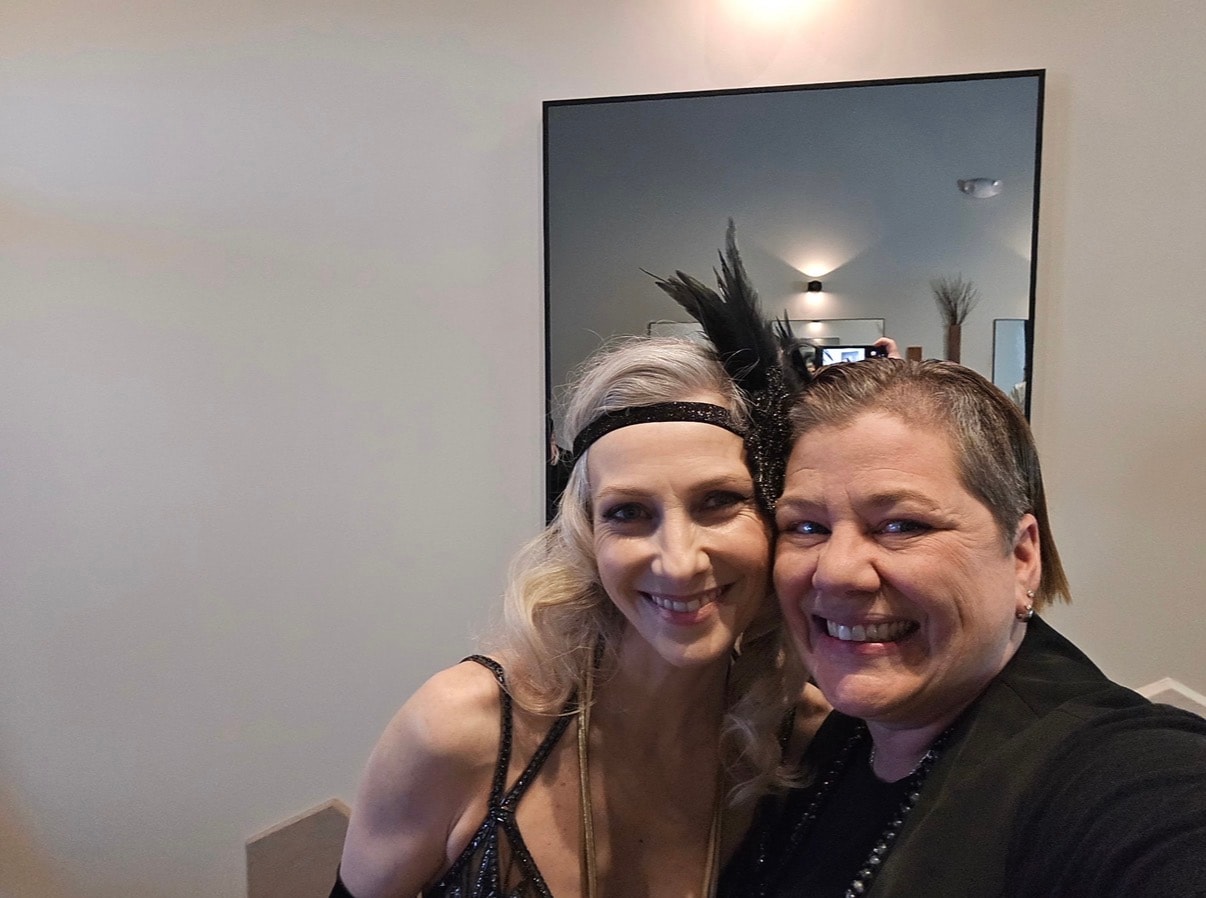 Two women in Gatsby costumes taking a selfie in the studio mirror