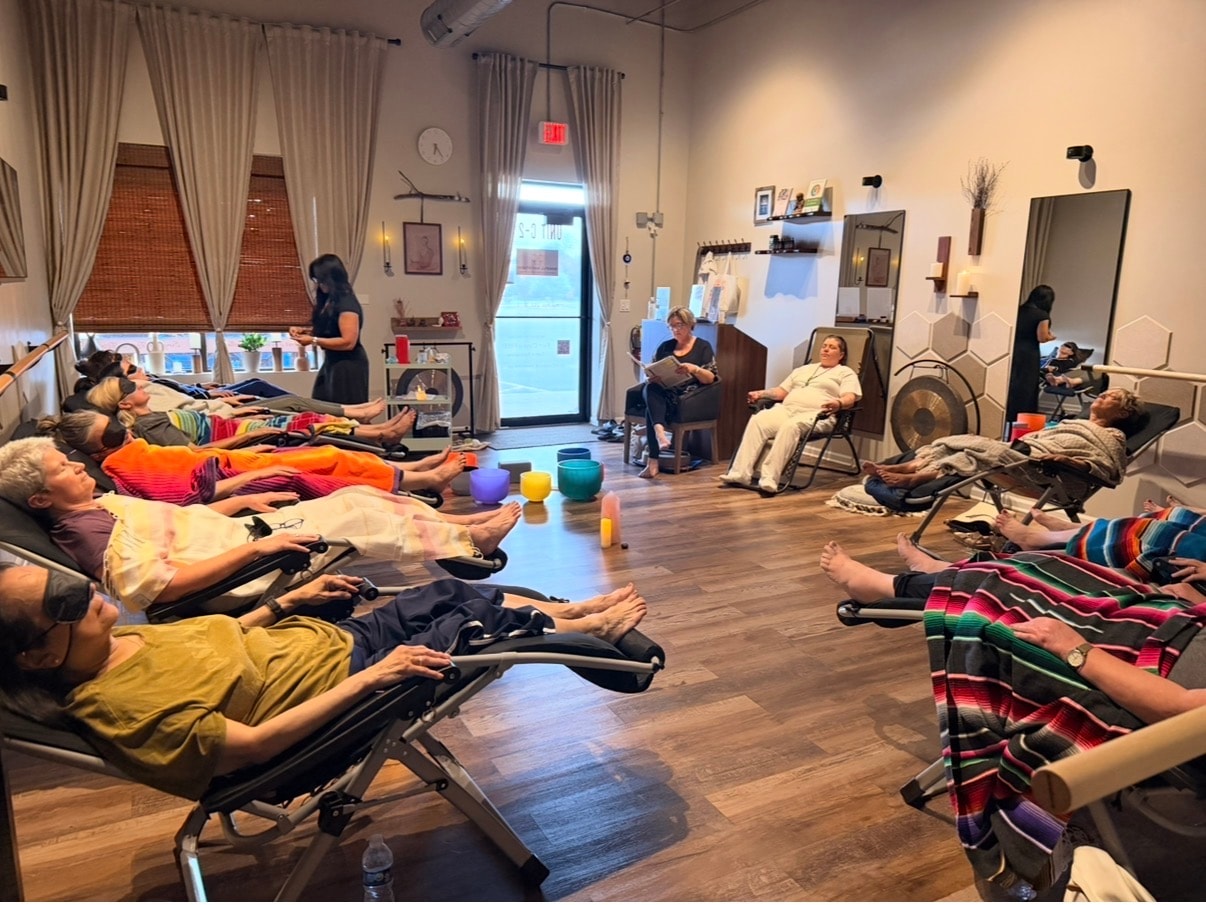 Large sound bath session with participants on floor, Ania facilitating