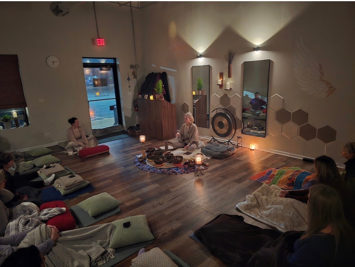 Wide shot of a sound bath in progress with participants on floor cushions