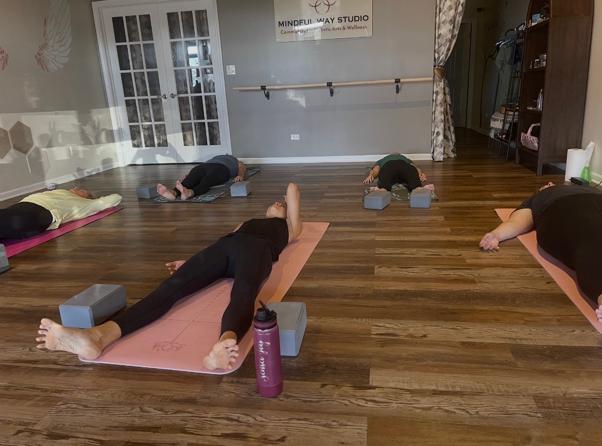 Yoga class with students lying on mats in a restorative pose