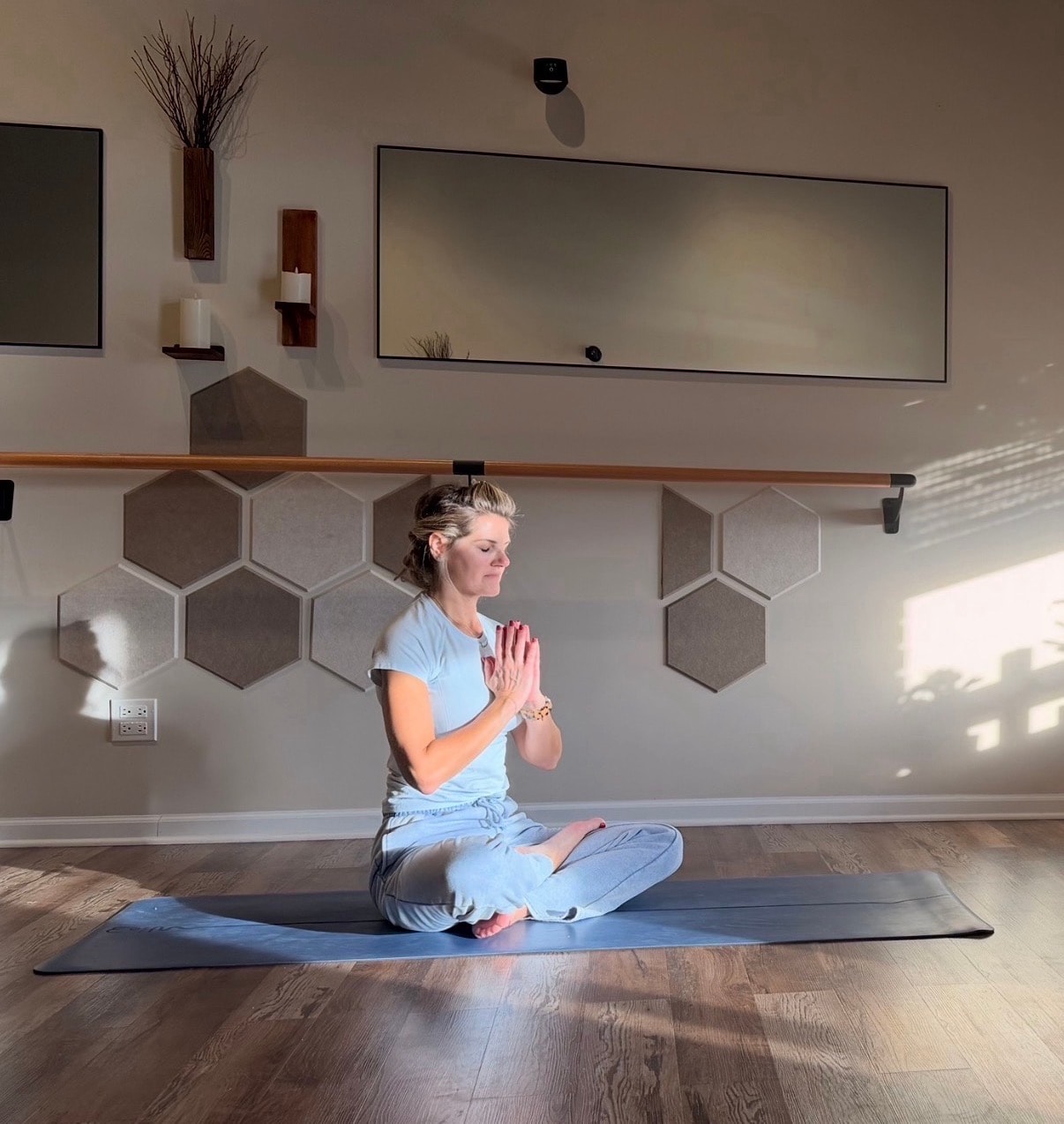 Ania seated in meditation surrounded by hexagonal wall panels