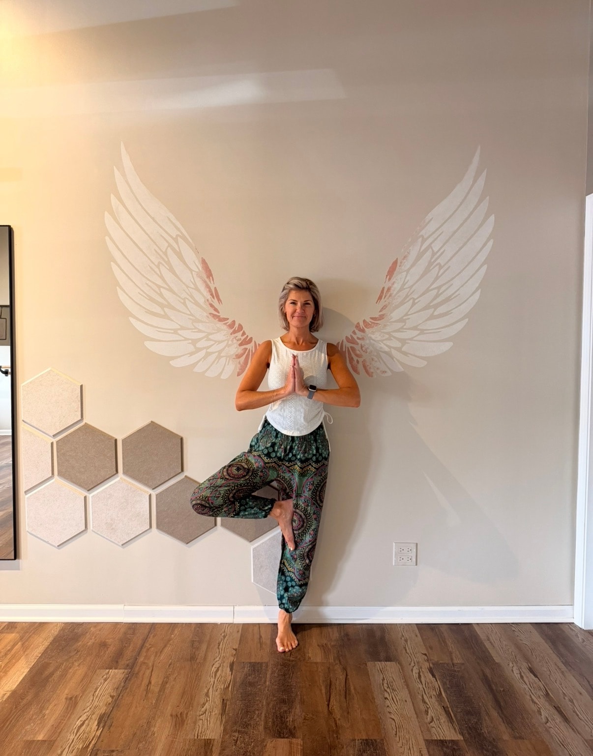 Ania in tree pose in front of the angel wings mural