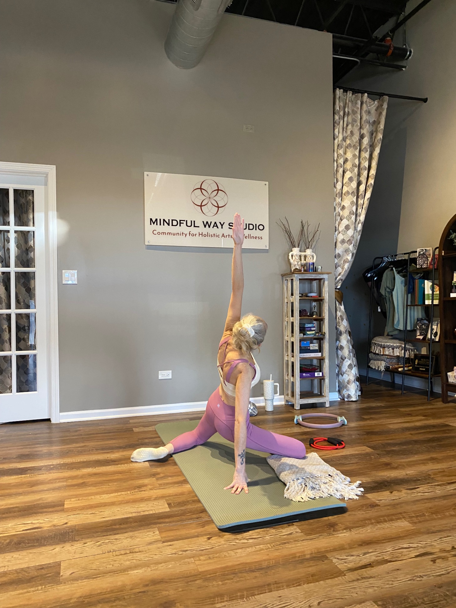 Pilates class at Mindful Way Studio Mokena IL — student in lateral stretch with Mindful Way Studio sign visible